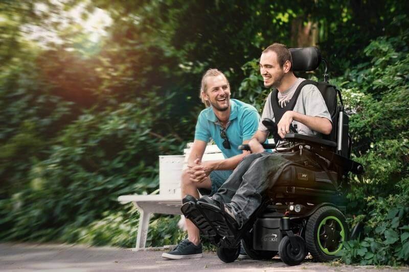 Power wheelchair user participating in community activities with a companion.